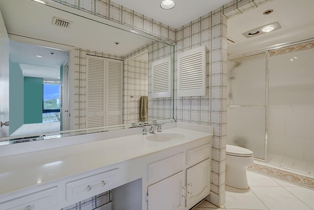 bathroom with tile walls, tile patterned flooring, vanity, walk in shower, and toilet