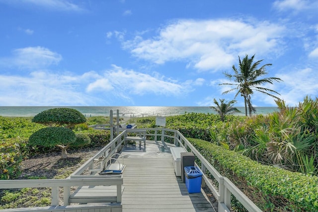 view of dock with a water view and a beach view