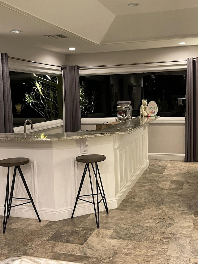 bar with white cabinets and stone countertops