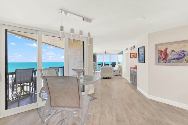 dining space featuring a water view, ceiling fan, and light hardwood / wood-style flooring