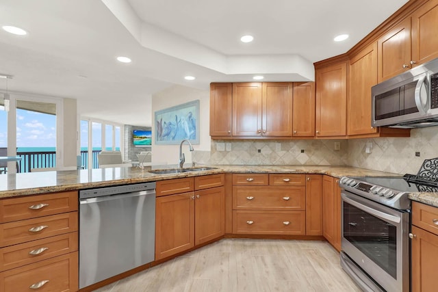 kitchen with light stone counters, stainless steel appliances, sink, and backsplash