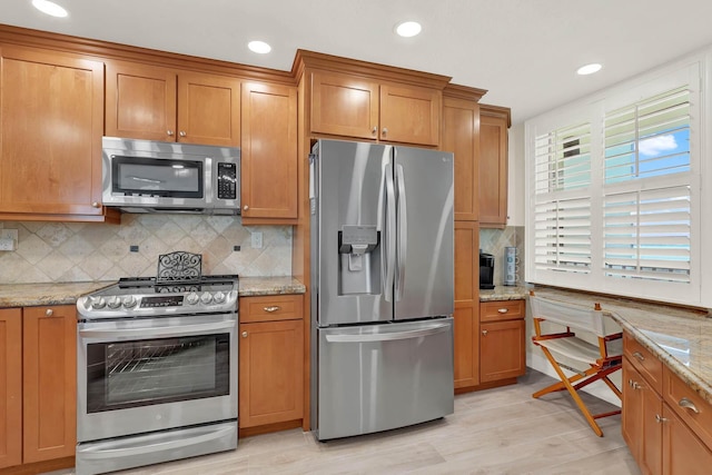 kitchen featuring light stone countertops, backsplash, and stainless steel appliances