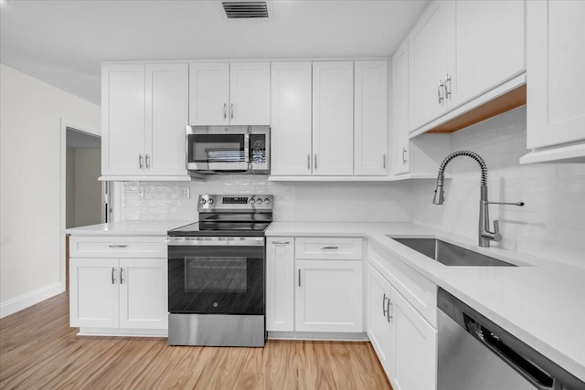1714 Palmland Dr Unit 1714, Boynton Beach, FL 33436 - kitchen featuring stainless steel appliances, a sink, backsplash, white cabinets, and light countertops