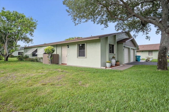 1714 Palmland Dr Unit 1714, Boynton Beach, FL 33436 - back of house with stucco siding, a lawn, a garage, and asphalt driveway