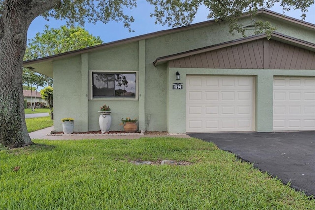 1714 Palmland Dr Unit 1714, Boynton Beach, FL 33436 - view of front facade with stucco siding, asphalt driveway, a front yard, and an attached garage