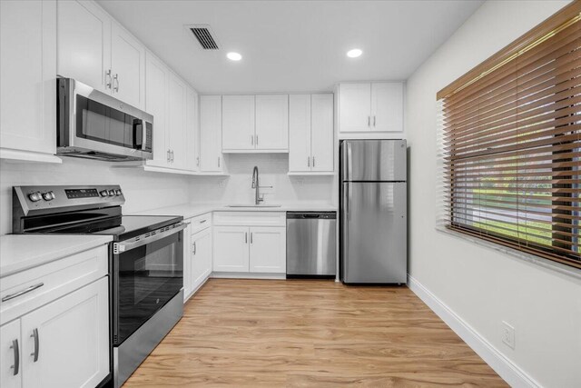 1714 Palmland Dr Unit 1714, Boynton Beach, FL 33436 - kitchen featuring stainless steel appliances, a sink, light countertops, white cabinetry, and light wood finished floors