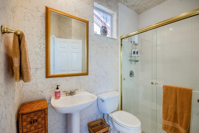 bathroom with a shower with shower door and toilet