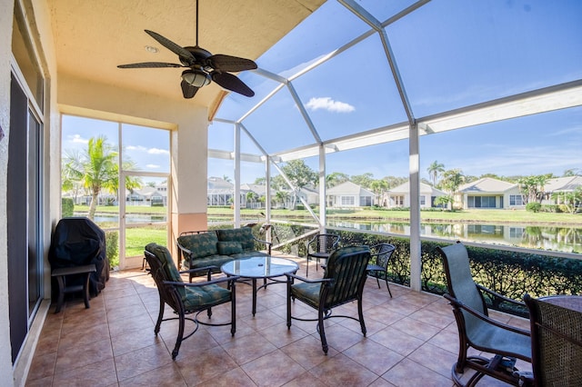 sunroom featuring ceiling fan and a water view