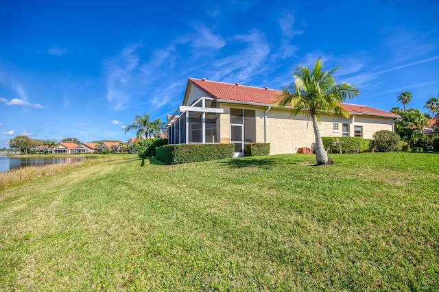 back of house featuring a water view and a lawn