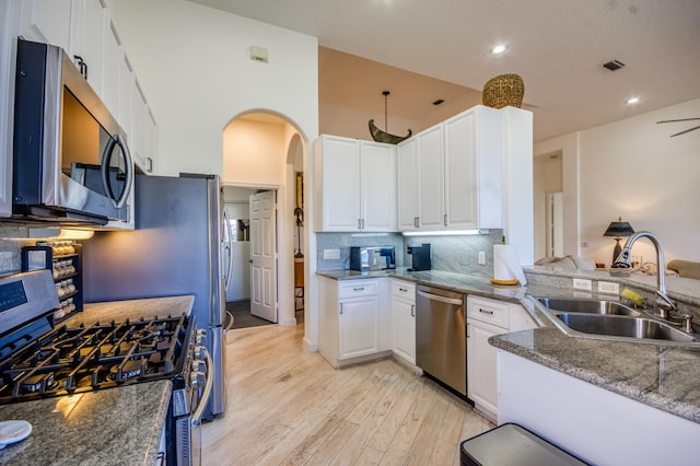 kitchen with white cabinetry, stainless steel appliances, sink, and stone counters