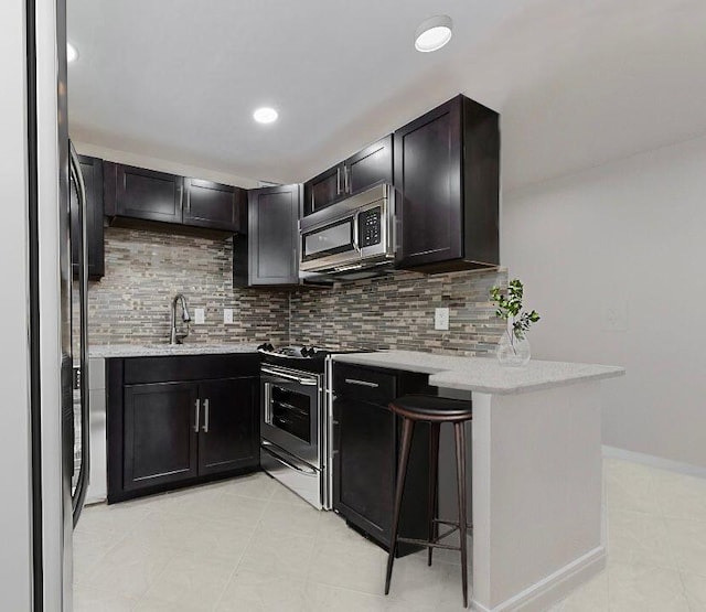 kitchen featuring a peninsula, appliances with stainless steel finishes, light stone countertops, and tasteful backsplash