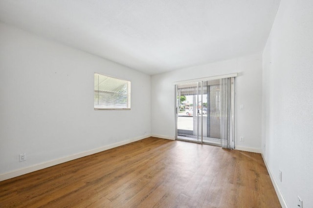 spare room featuring wood finished floors, a wealth of natural light, and baseboards