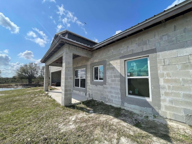 view of side of property featuring a lawn, a patio, and a water view