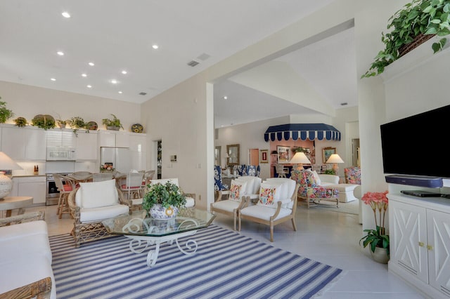 living room with light tile patterned floors, a high ceiling, visible vents, and recessed lighting