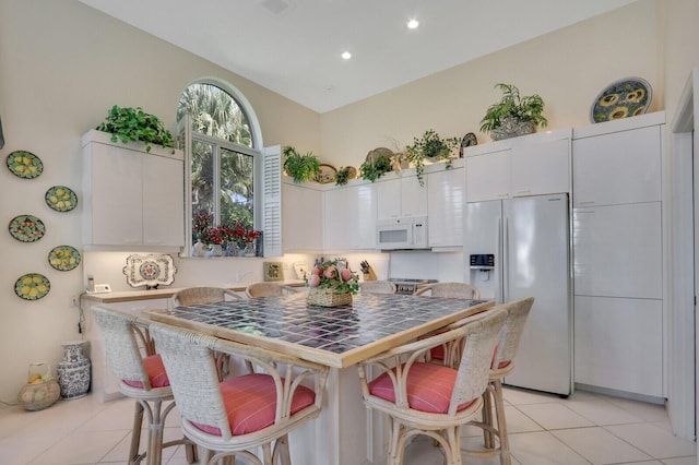 kitchen featuring light countertops, a breakfast bar, white appliances, and white cabinets