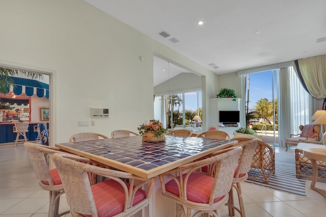 dining space featuring light tile patterned floors, vaulted ceiling, a wall of windows, and visible vents