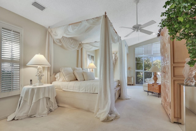 bedroom with lofted ceiling, ceiling fan, a textured ceiling, light colored carpet, and visible vents