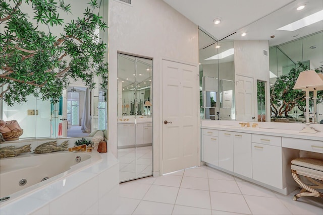 full bath with visible vents, vanity, a tub with jets, and tile patterned floors