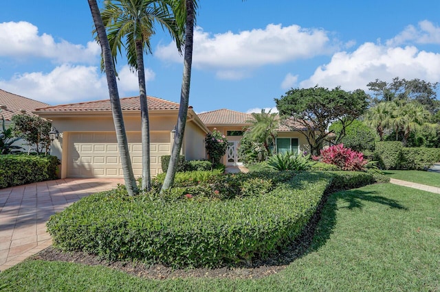 mediterranean / spanish house featuring a tile roof, driveway, an attached garage, and stucco siding