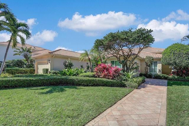 view of front of home with a front lawn, a tiled roof, an attached garage, and stucco siding