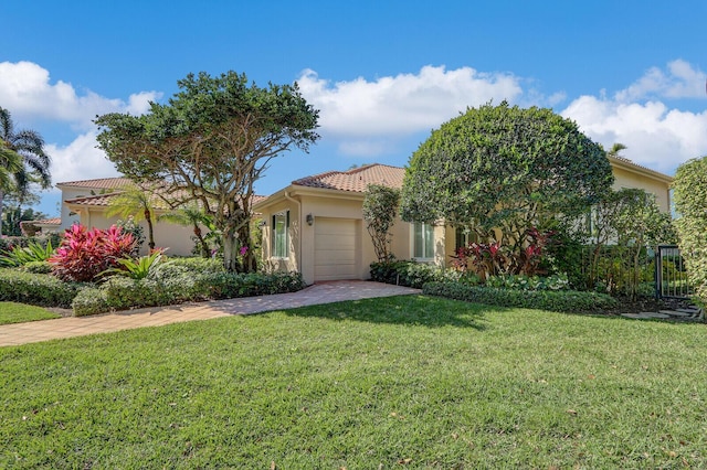 view of front of property featuring a garage, a tiled roof, decorative driveway, a front yard, and stucco siding