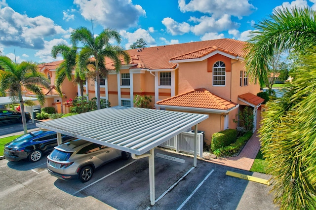 exterior space featuring stucco siding, uncovered parking, and a tile roof