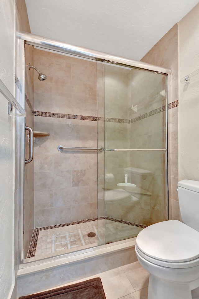 bathroom with tile patterned flooring, a shower with door, and toilet