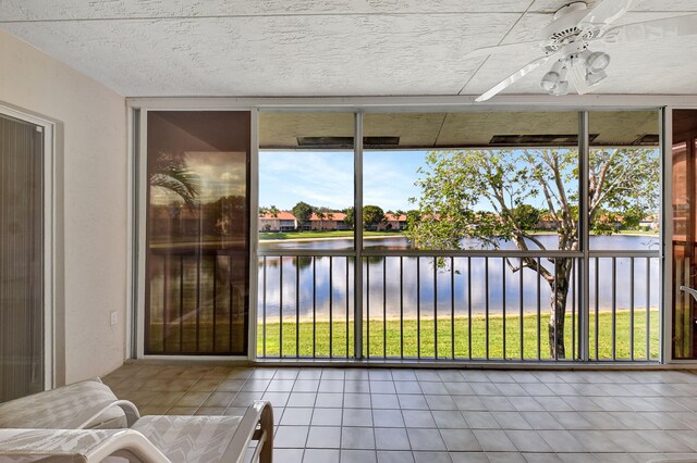 sunroom featuring ceiling fan and a water view