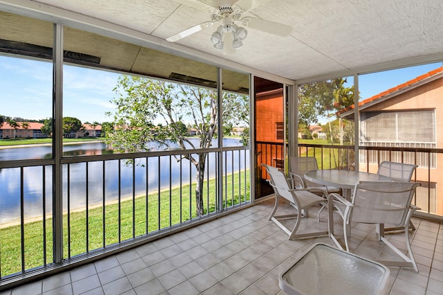 sunroom / solarium featuring a water view and ceiling fan