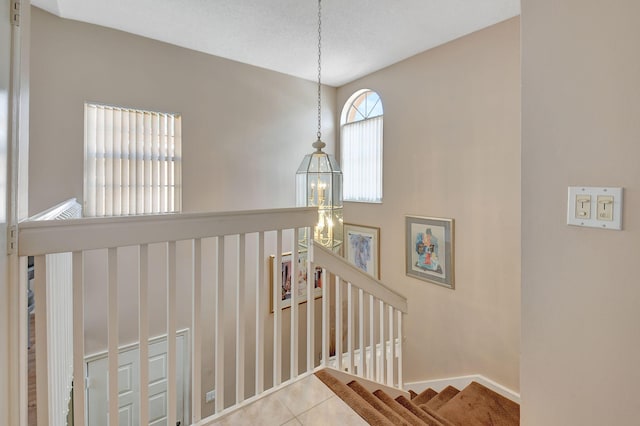 stairs with a chandelier and tile patterned flooring