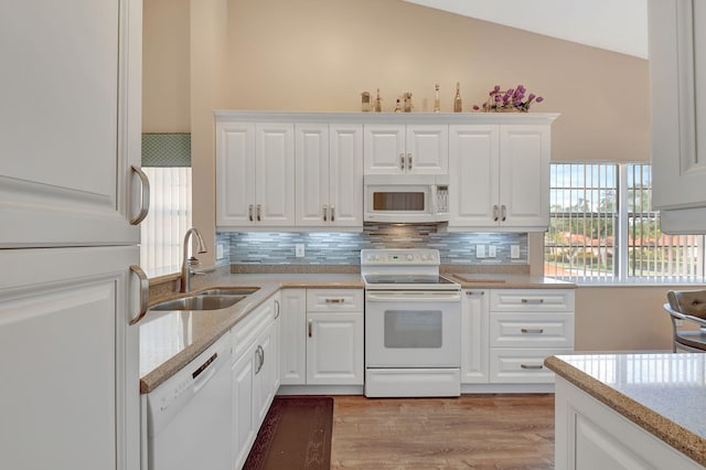 kitchen featuring white cabinetry, white appliances, backsplash, and a sink