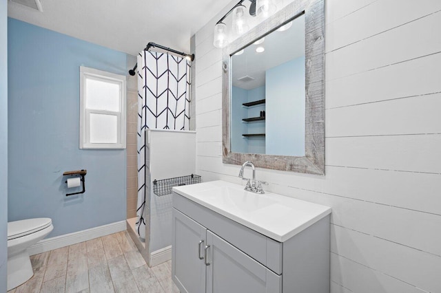 bathroom featuring vanity, toilet, hardwood / wood-style floors, and a tile shower