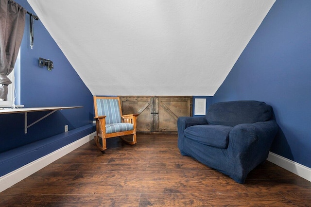 living area featuring dark hardwood / wood-style flooring, vaulted ceiling, and a textured ceiling