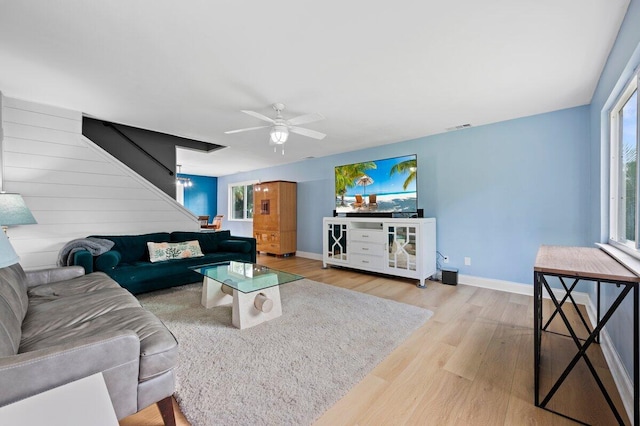 living room featuring ceiling fan, a healthy amount of sunlight, light wood-type flooring, and wood walls