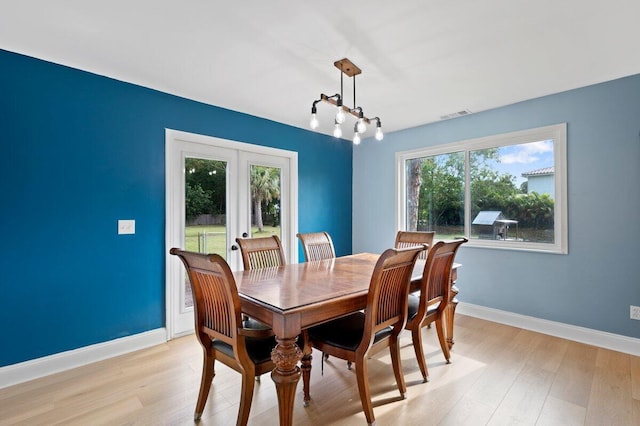 dining space with an inviting chandelier, plenty of natural light, light hardwood / wood-style flooring, and french doors