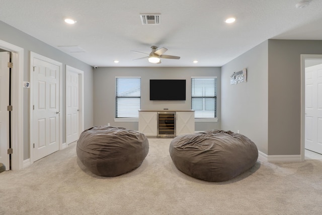 living area featuring light colored carpet, beverage cooler, and ceiling fan