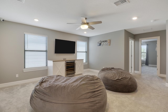 carpeted living room featuring a wealth of natural light, wine cooler, and ceiling fan
