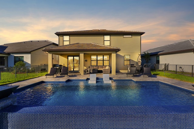 back house at dusk with outdoor lounge area, a fenced in pool, and a patio