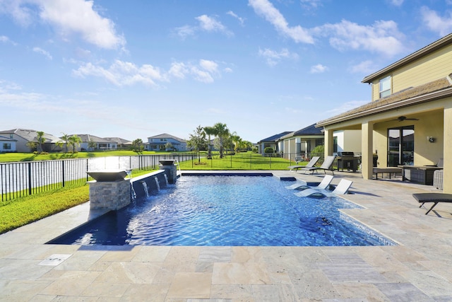 view of pool featuring pool water feature, a lawn, ceiling fan, a grill, and a patio