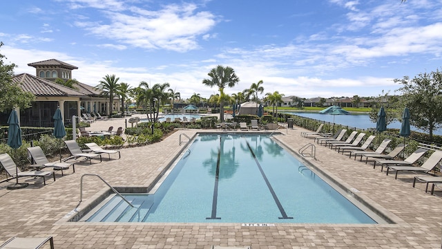 view of swimming pool with a patio and a water view