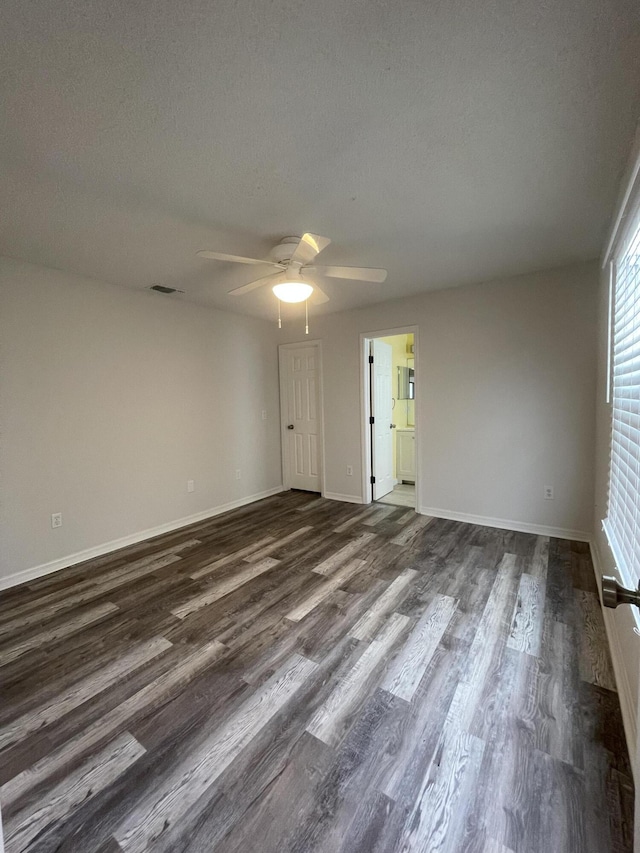 empty room with ceiling fan, dark hardwood / wood-style floors, and a textured ceiling