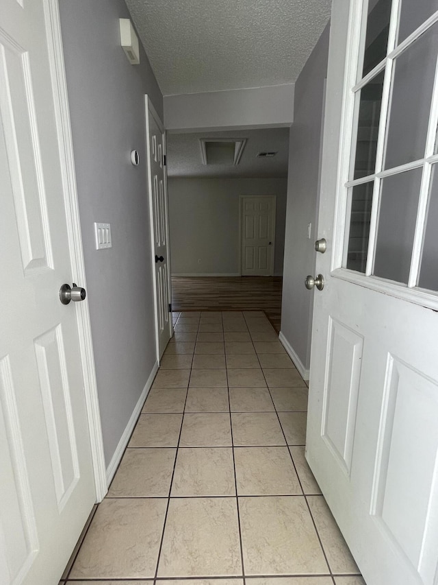 hall featuring light tile patterned floors and a textured ceiling