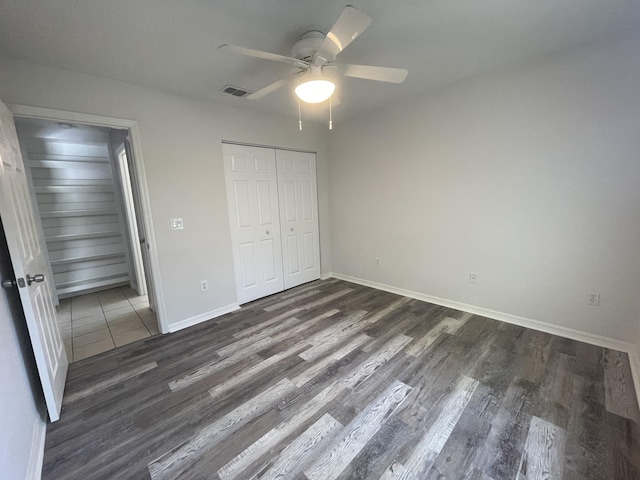 unfurnished bedroom with a closet, dark hardwood / wood-style floors, and ceiling fan