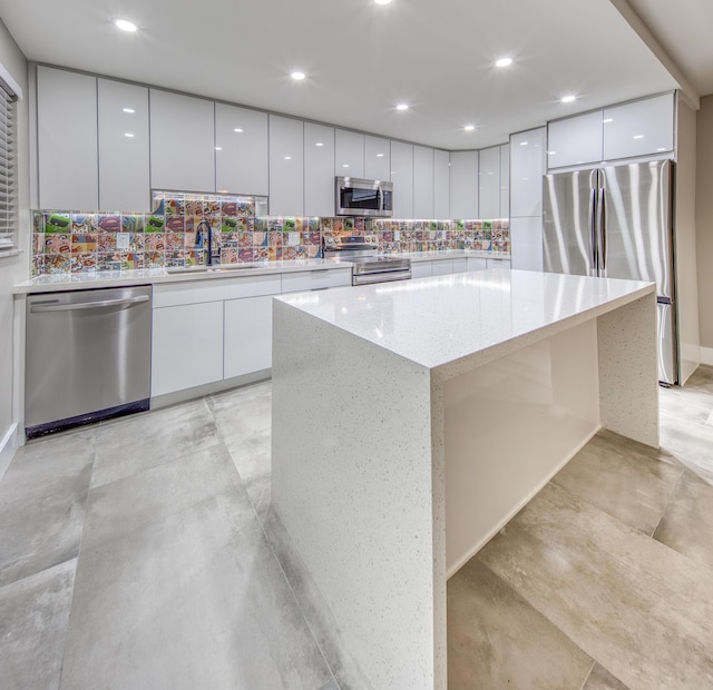 kitchen featuring sink, white cabinetry, a center island, stainless steel appliances, and backsplash