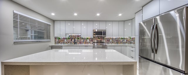 kitchen featuring sink, appliances with stainless steel finishes, light stone counters, tasteful backsplash, and white cabinets