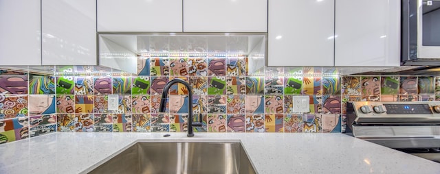 kitchen featuring stainless steel appliances, sink, white cabinets, and light stone counters