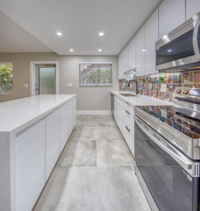 kitchen with sink, white cabinetry, backsplash, plenty of natural light, and stainless steel appliances