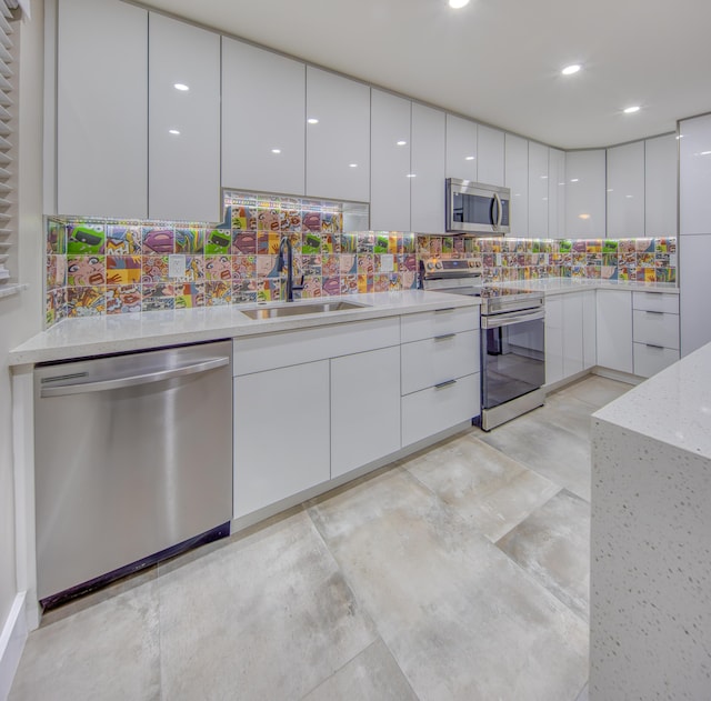 kitchen featuring sink, white cabinetry, light stone counters, stainless steel appliances, and backsplash