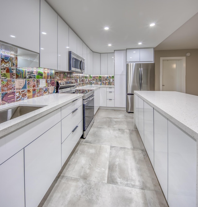 kitchen with white cabinetry, appliances with stainless steel finishes, light stone counters, and backsplash