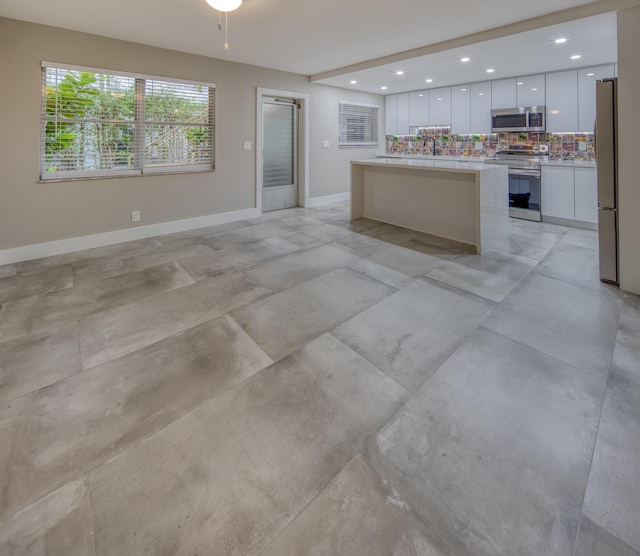 kitchen featuring decorative backsplash, stainless steel appliances, white cabinets, and a kitchen island